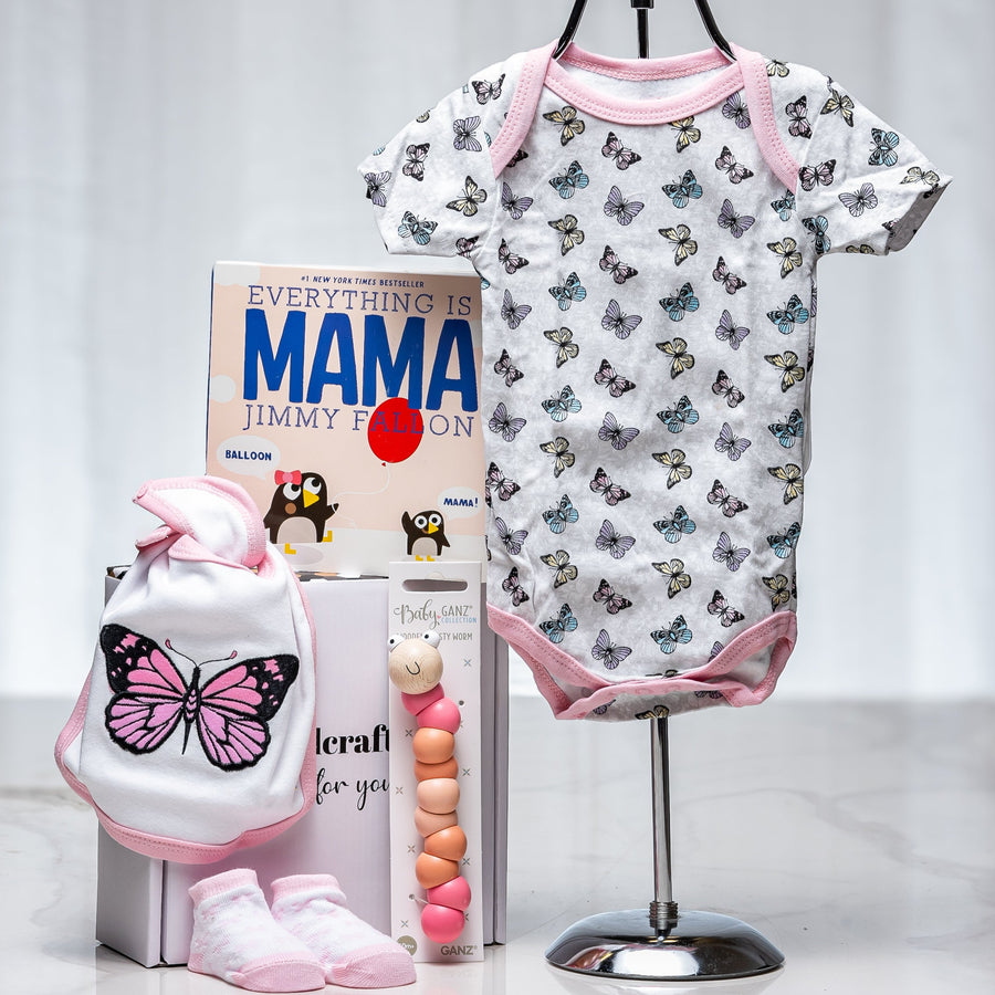 Soar baby girl gift with a butterfly print onesie, the book Mama by Jimmy Fallon and pink shoes