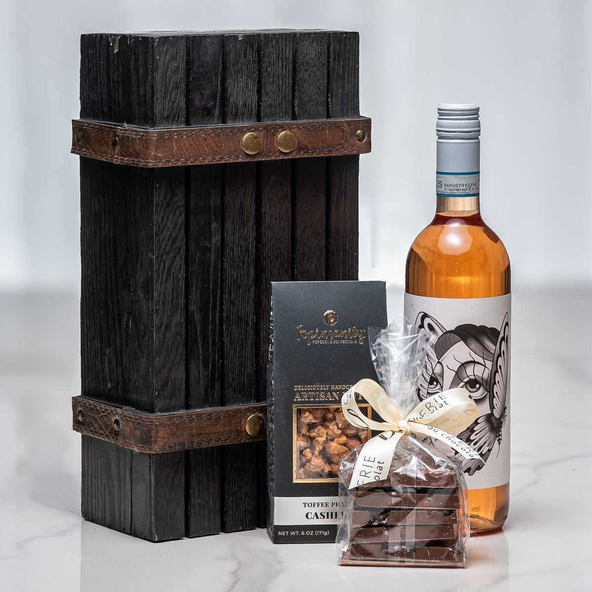 Solo Mio gift with a bottle of rose wine, chocolate and nuts presented against a dark wood crate