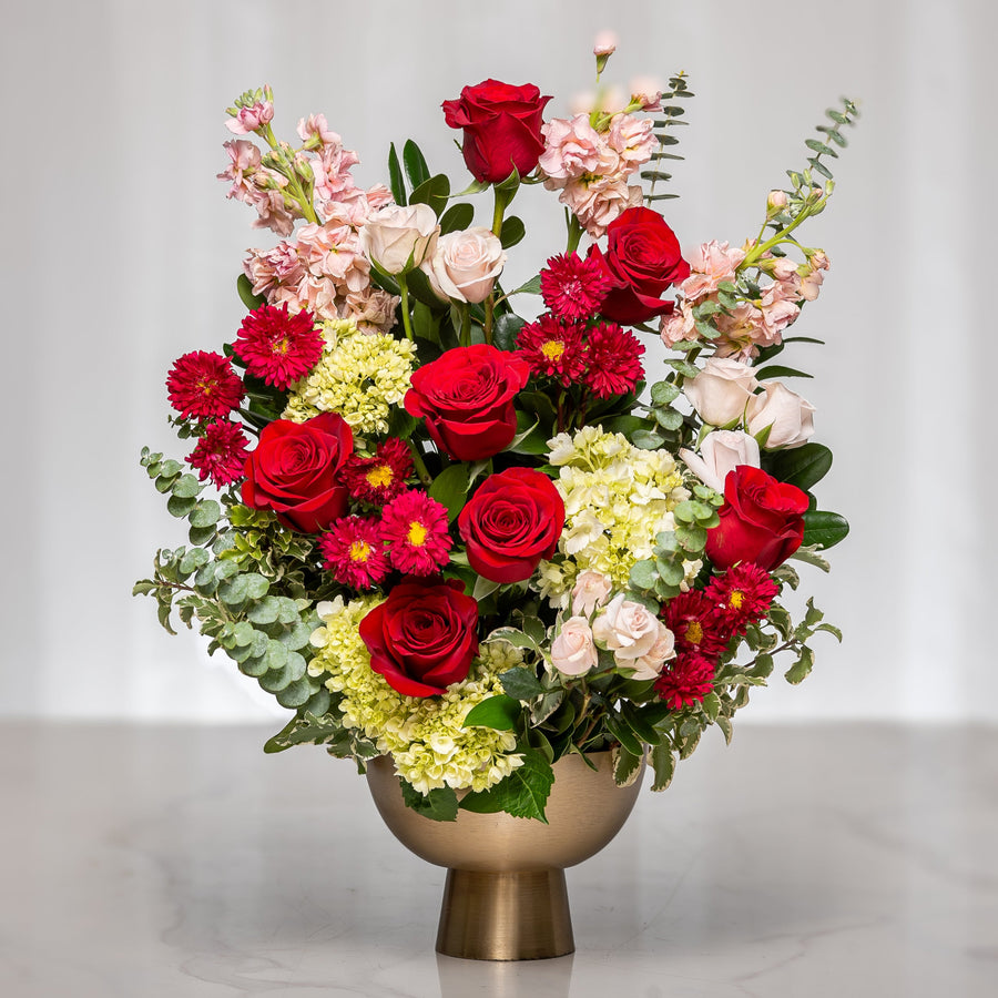 Sweet Serenade arrangement of red roses, gerberas and mixed blooms in a gold footed vase