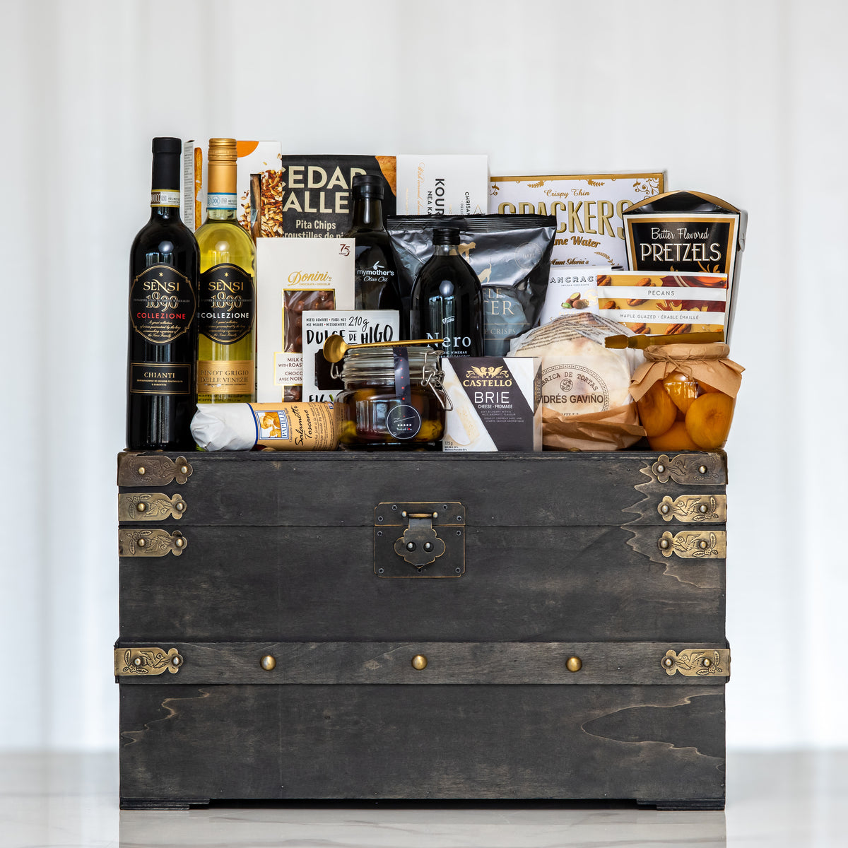 Treasure Trove large dark trunk with two bottles of wine, olive oil, crackers and pretzels