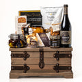 Treasure Trove Small: a rustic wooden trunk with black metal detailing holding a bottle of Biscardo Neropasso, My Mother's olives, peach halves, Castello brie, tapenade and truffle crisps