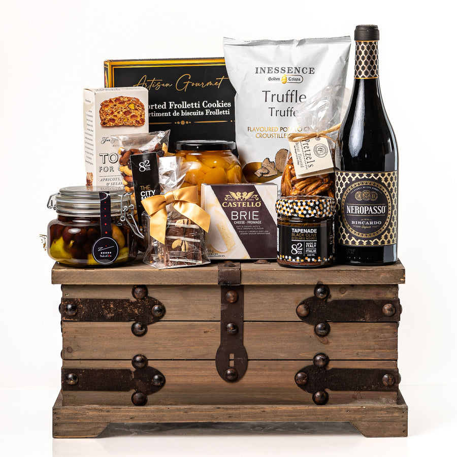 Treasure Trove Small: a rustic wooden trunk with black metal detailing holding a bottle of Biscardo Neropasso, My Mother's olives, peach halves, Castello brie, tapenade and truffle crisps