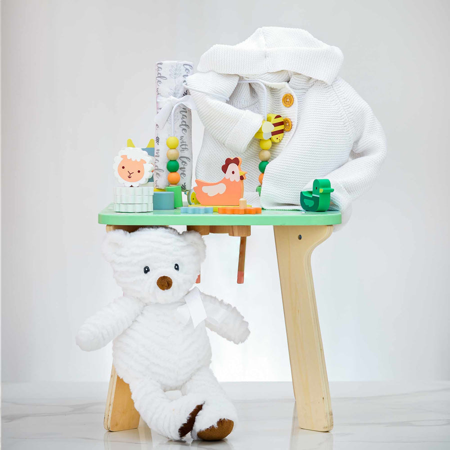 Janod wooden activity table with toys, shown beside a white plush teddy bear
