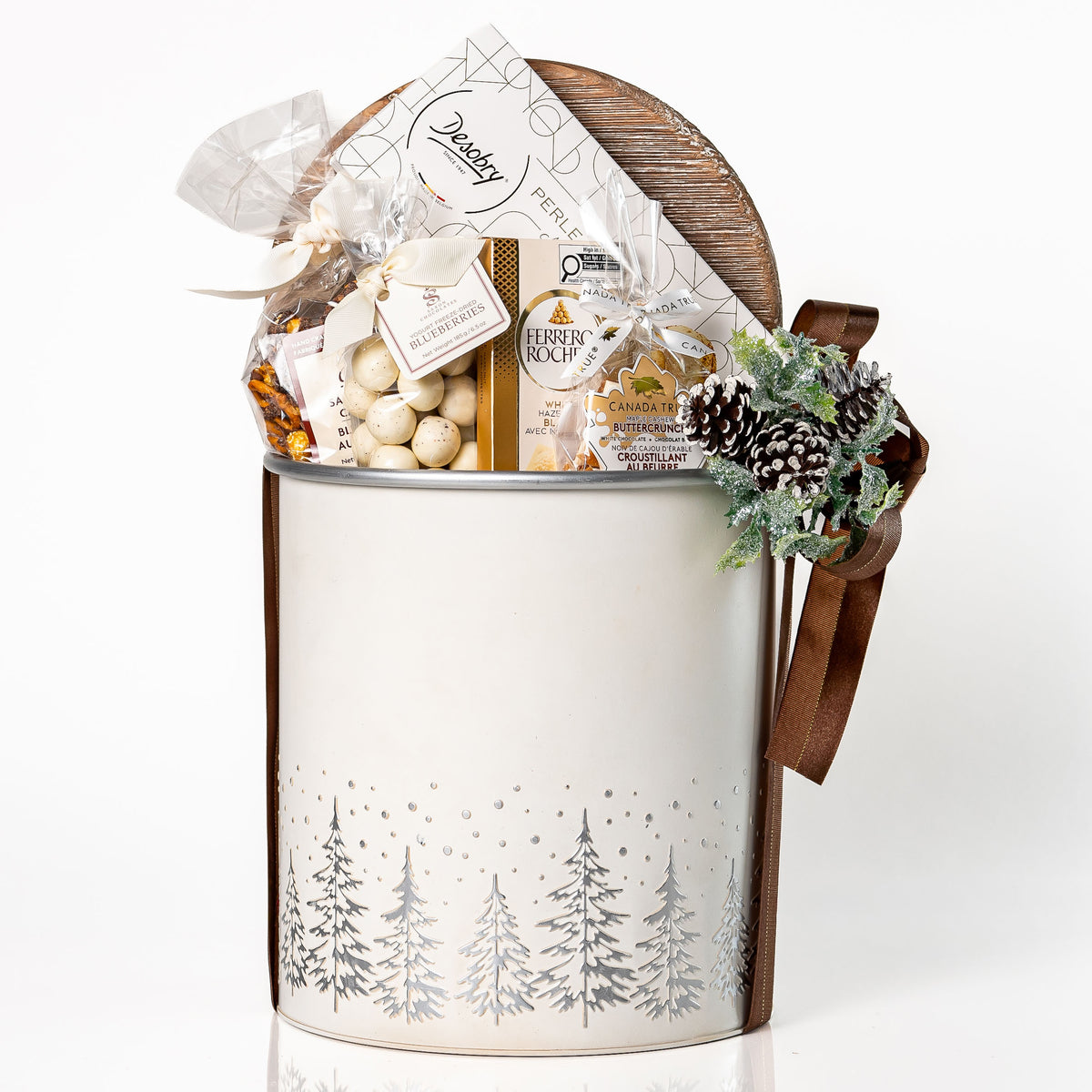 Winter Wonderland: a white tub with a silver pine tree design and a wooden lid, topped with a pinecone and filled with a Ferrero Rocher bar, Desobry biscuits, yogurt covered blueberries and caramel cashew popcorn