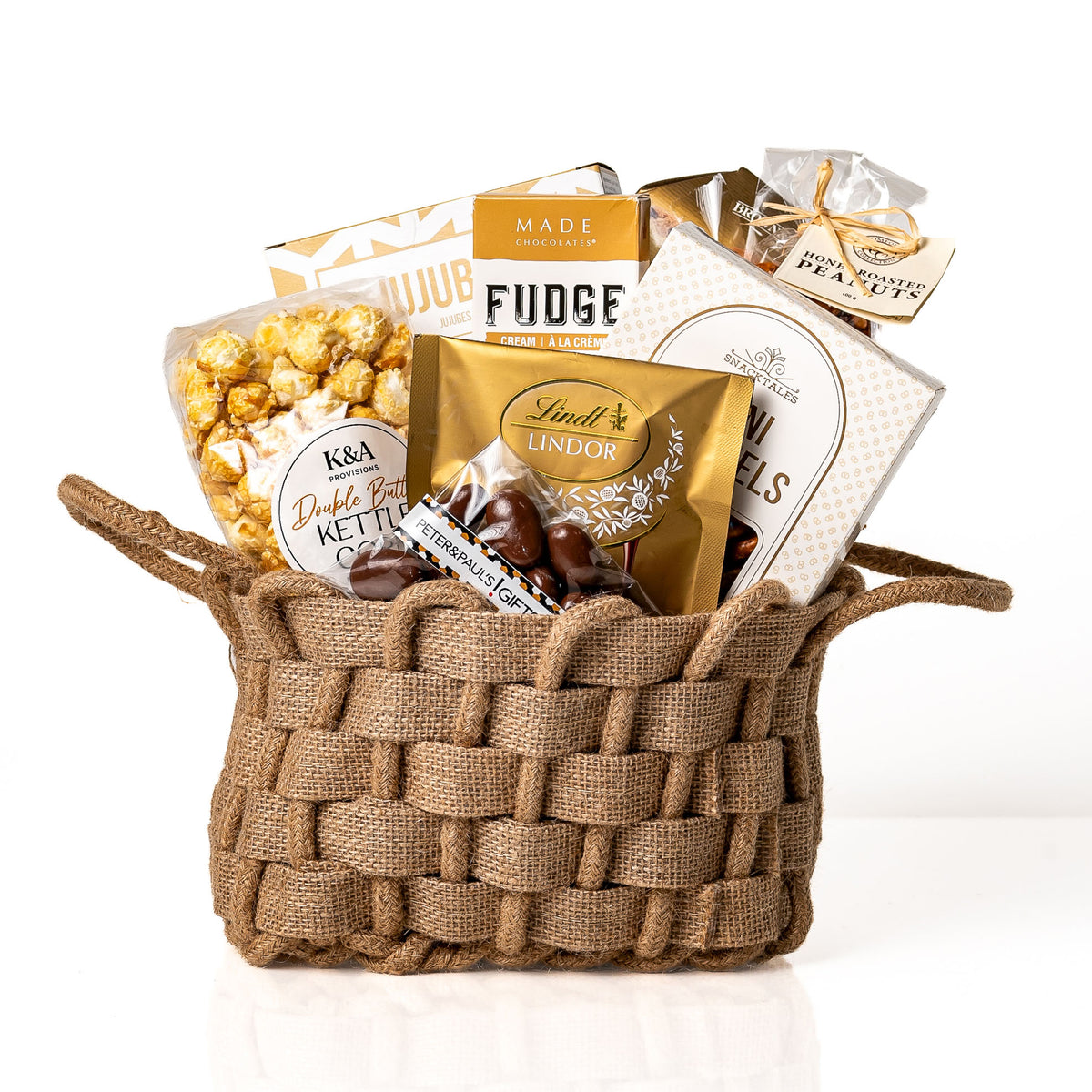 Woven Wonders Small: a burlap woven basket with handles holding fudge, Lindt Lindor truffles, double butter kettle corn, chocolate covered almonds, jujubes and mini pretzels