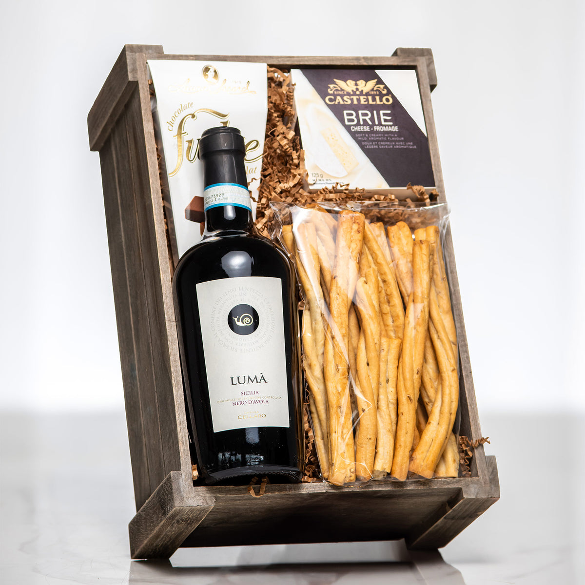 Box o Wine wooden crate with a bottle of red wine, grissini and Castello brie