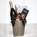 Celebration gift with a bottle of sparkling wine in a silver ice bucket, chocolates and nuts