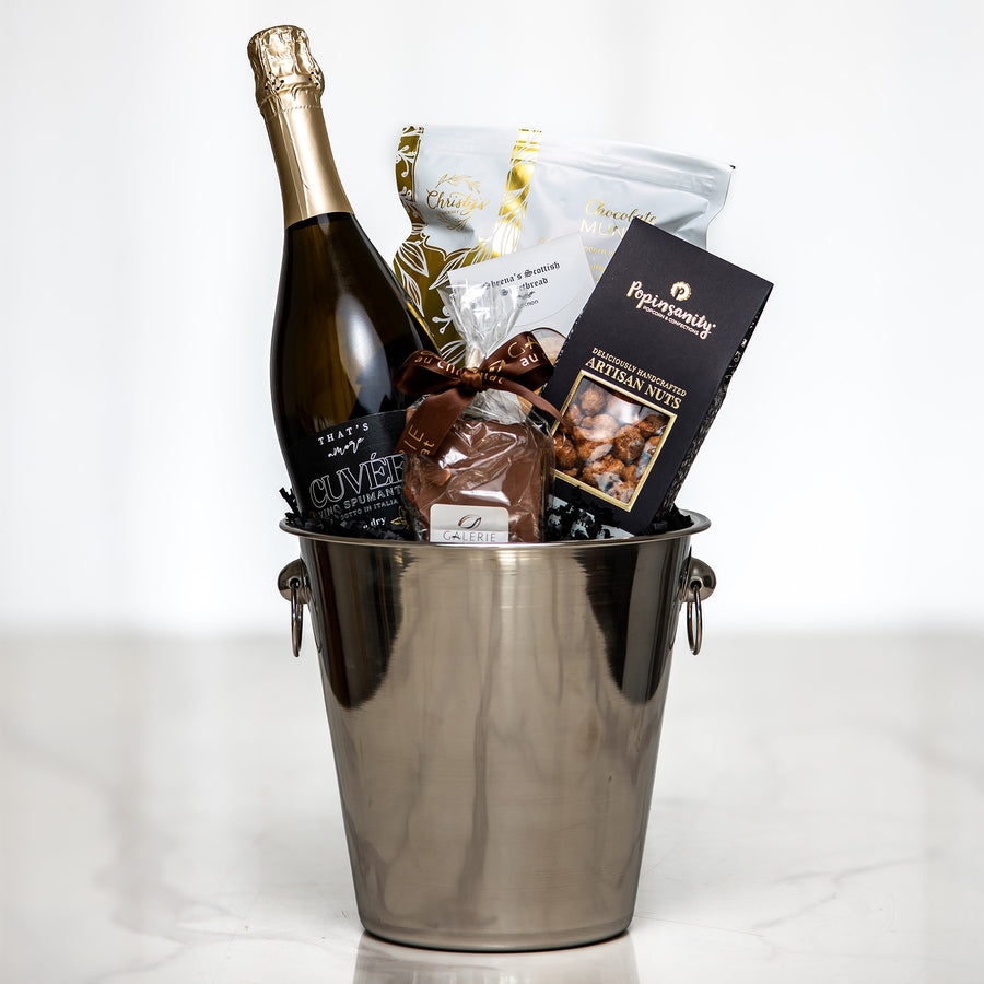 Celebration gift with a bottle of sparkling wine in a silver ice bucket, chocolates and nuts