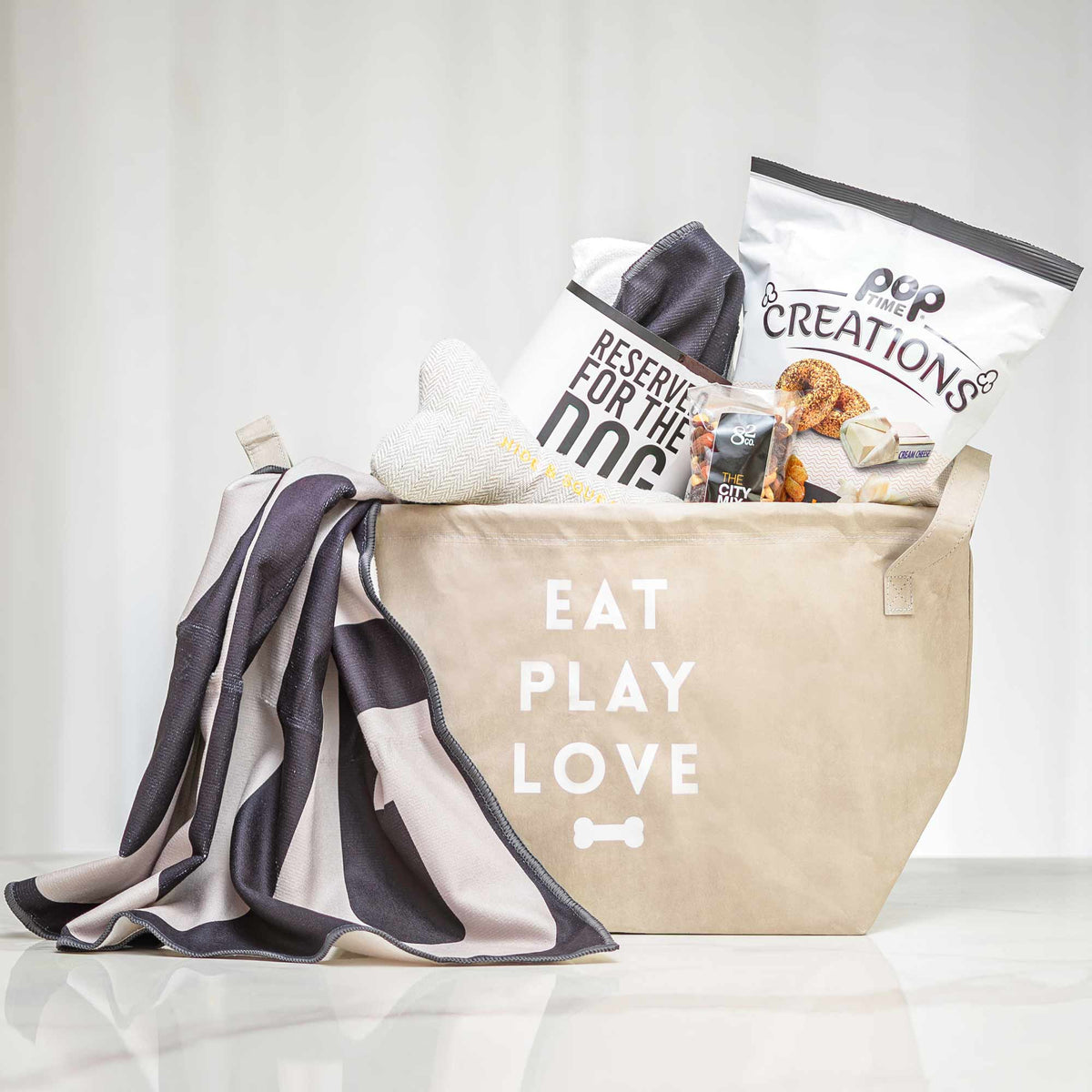 Eat Play Love dog gift tote with a blanket, treats and popcorn in a canvas bag