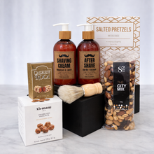 Load image into Gallery viewer, The Gentleman's Box close-up showing shaving cream, after shave, wooden shaving brush, City Mix nuts and Cashew Roca
