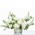 Angelic arrangement of white roses, stock and delphinium in a fluted white pot