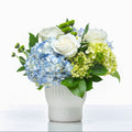 Charming arrangement of blue hydrangea, white roses and green hydrangea in a fluted white pot