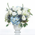 Blue Skies arrangement of blue hydrangea, white roses and thistle in a white footed vase