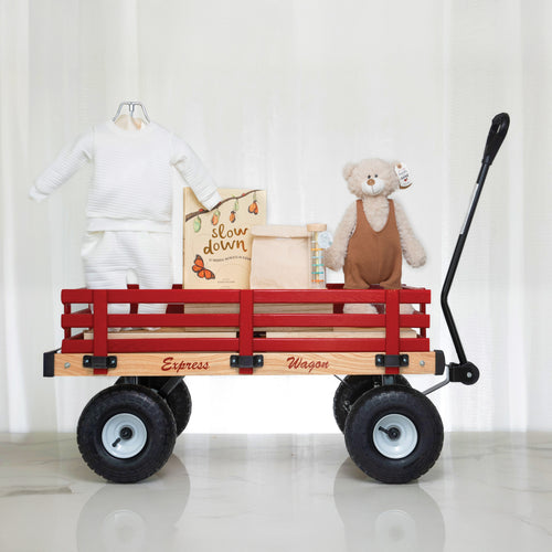 Red Wagon baby gift, a wooden pull wagon holding a white outfit, a keepsake box and a plush bear