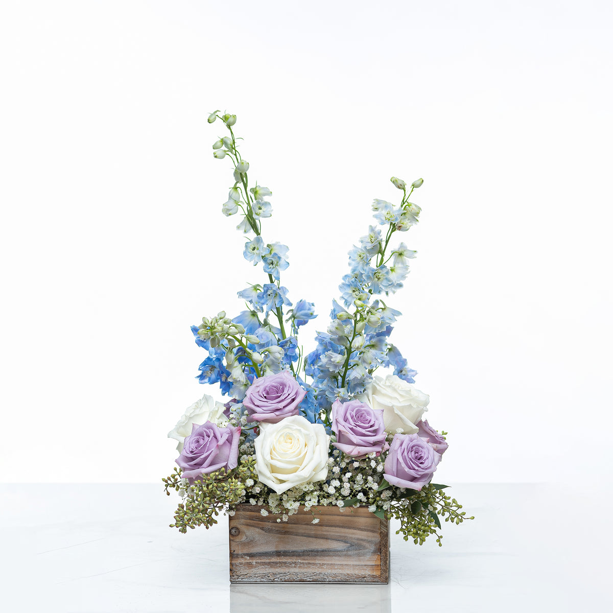Vienna arrangement of blue delphinium, lilac and white roses in a rustic wooden box
