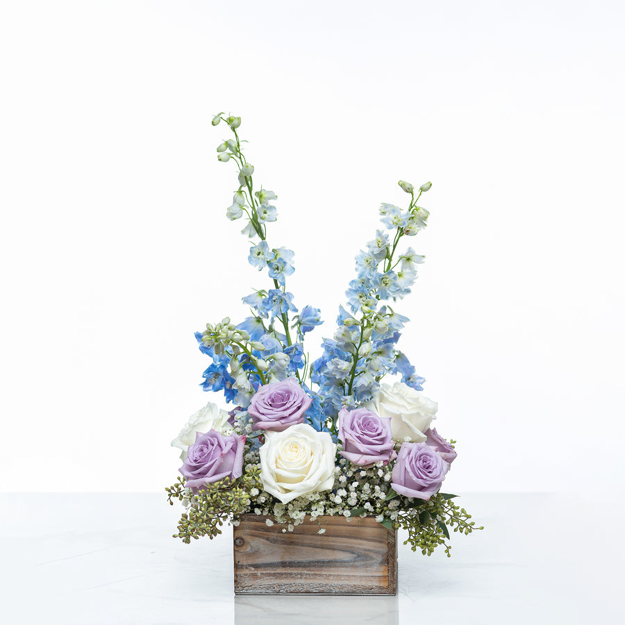 Vienna arrangement of blue delphinium, lilac and white roses in a rustic wooden box