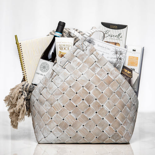 Woven Wonders grey woven basket with a notebook, a bottle of wine, brie and gourmet snacks